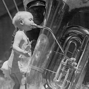 An nearly naked infant toots a tuba many times his size - Art Print