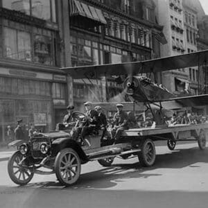 Biplane with spinning propeller is towed down Fifth Avenue New York for July 4th Parade - Art Print