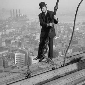Cameraman in suit holds onto cable as he walks unharnessed over a skyscraper's steel girders #2 - Art Print