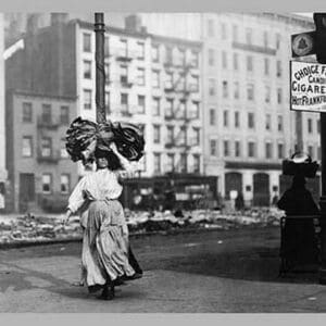 Immigrant Woman Walks Down Street Carrying a Pile of Clothing on Her Head - Art Print